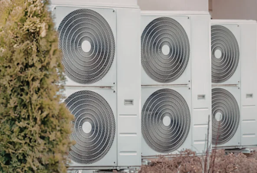 Multiple commercial heat pump outdoor condenser units installed outside a building, commonly used for energy-efficient heating and cooling in commercial HVAC systems.