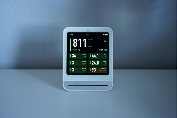 A modern, white digital monitor displays real-time indoor environmental data, including carbon dioxide levels at 811 ppm, humidity at 44.1%, and a temperature of 24.0°C.