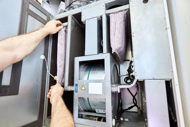 Hands replacing a filter bag inside a commercial HVAC air handling unit
