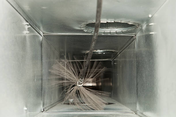 Rotating cleaning brush scrubbing the inside of a galvanized metal air duct